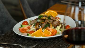 A plate of food with a glass of red wine and a bottle in the background.