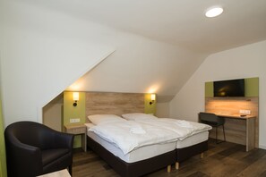 A modern bedroom with a bed, bedside tables, a desk, and a chair. - ROCA Restaurant & Hotel (Oberursel)