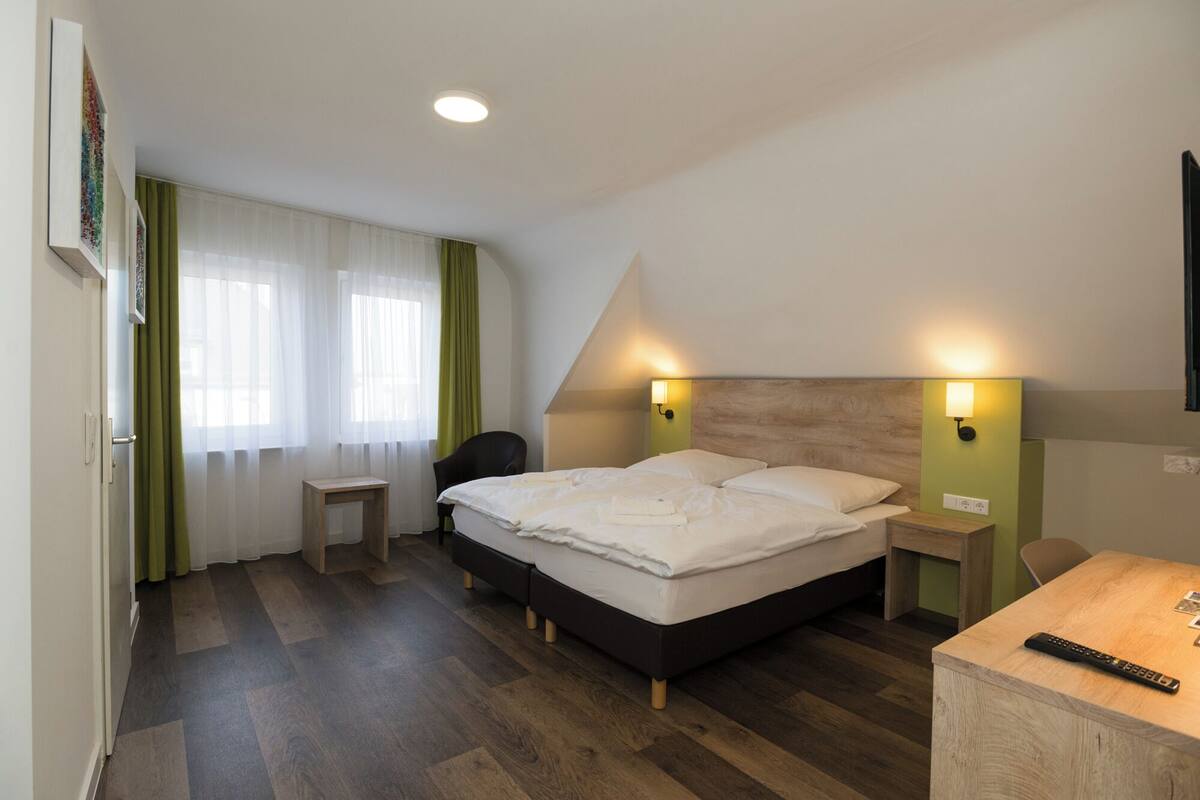A modern hotel room with a large bed, a desk, and a chair.
