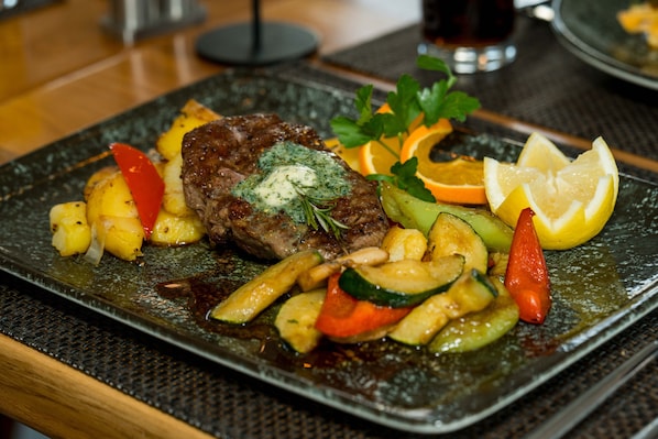 A plated dish with steak, vegetables, and a garnish.