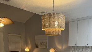 A modern kitchen with a central island, white cabinetry, and a hanging light fixture. - Isle Be Back (Miramar Beach)