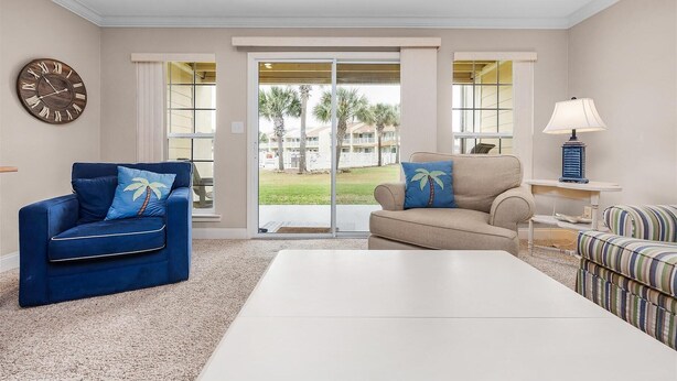 A living room with a blue sofa, beige sofa, and striped couch, a white coffee table, a clock, and a lamp. - Meet Me at The Gulf (Destin)