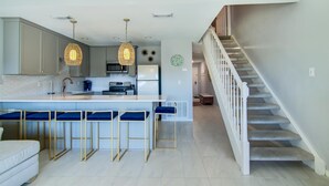 Een moderne keuken met een centraal eiland, barkrukken en hanglampen.