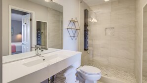 Een moderne badkamer met een wit wastafel, toilet en een douche met glazen wanden.