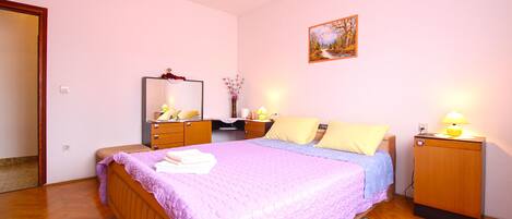 A bedroom with a bed, bedside tables, a dresser, a mirror, and a painting on the wall.