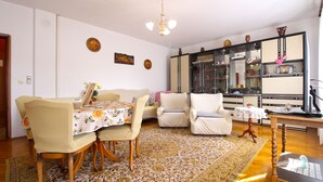 Un coin repas avec une table dressée pour deux personnes, un canapé et un meuble avec des portes en verre.