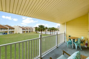 A balcony with a view of a swimming pool, a grassy area, and multiple buildings in the background. - 7E, Shell We Stay? (Miramar Beach)
