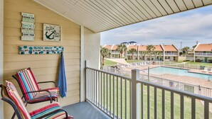 Ein Balkon mit gestreiften Stühlen, ein Pool und Blick auf einen Resort-Komplex.