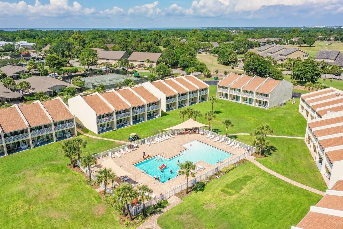 A hotel with multiple buildings, a central swimming pool, and surrounding greenery.