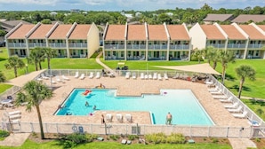 Ein Hotel mit Swimmingpool, umgeben von Liegestühlen und Palmen.