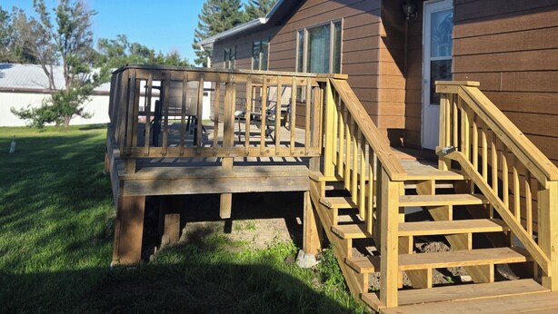 A wooden deck with a staircase leading to a house with a brown exterior. - LaCreek Lodge-5 beds (Martin)