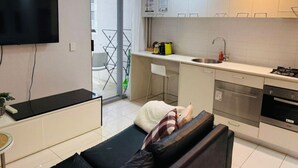 A modern kitchen with a flat-screen TV, a dining area with a sofa, and a view of the outside. - Urban Redefined - Centre of CBD (Brisbane City)