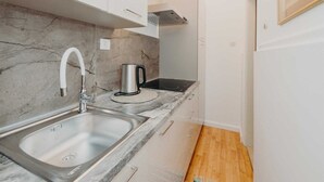 A compact kitchen with a marble backsplash, stainless steel sink, and a kettle on the countertop. - VILLA ROSSELLA 2 Studio (La Rosa) (Rovinj)