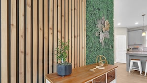 A modern kitchen with a wooden countertop, a potted plant, and a decorative wall.