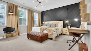 A modern bedroom with a bed, desk, and ottoman.