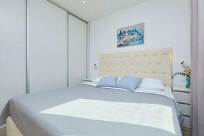 Une chambre moderne avec un grand lit, une tête de lit, une table de chevet avec une lampe et un tableau au mur.