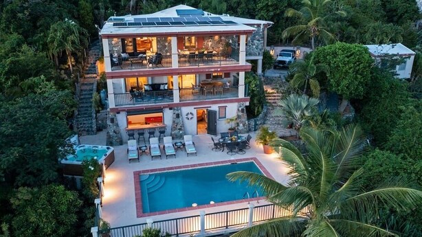 Une maison à deux étages dotée d’une piscine, d’un espace extérieur aménagé et de panneaux solaires.