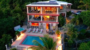 A two-story building with a pool, outdoor seating, and a hot tub.