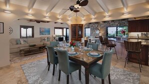 A spacious dining area with a large wooden table set for six, surrounded by teal chairs.