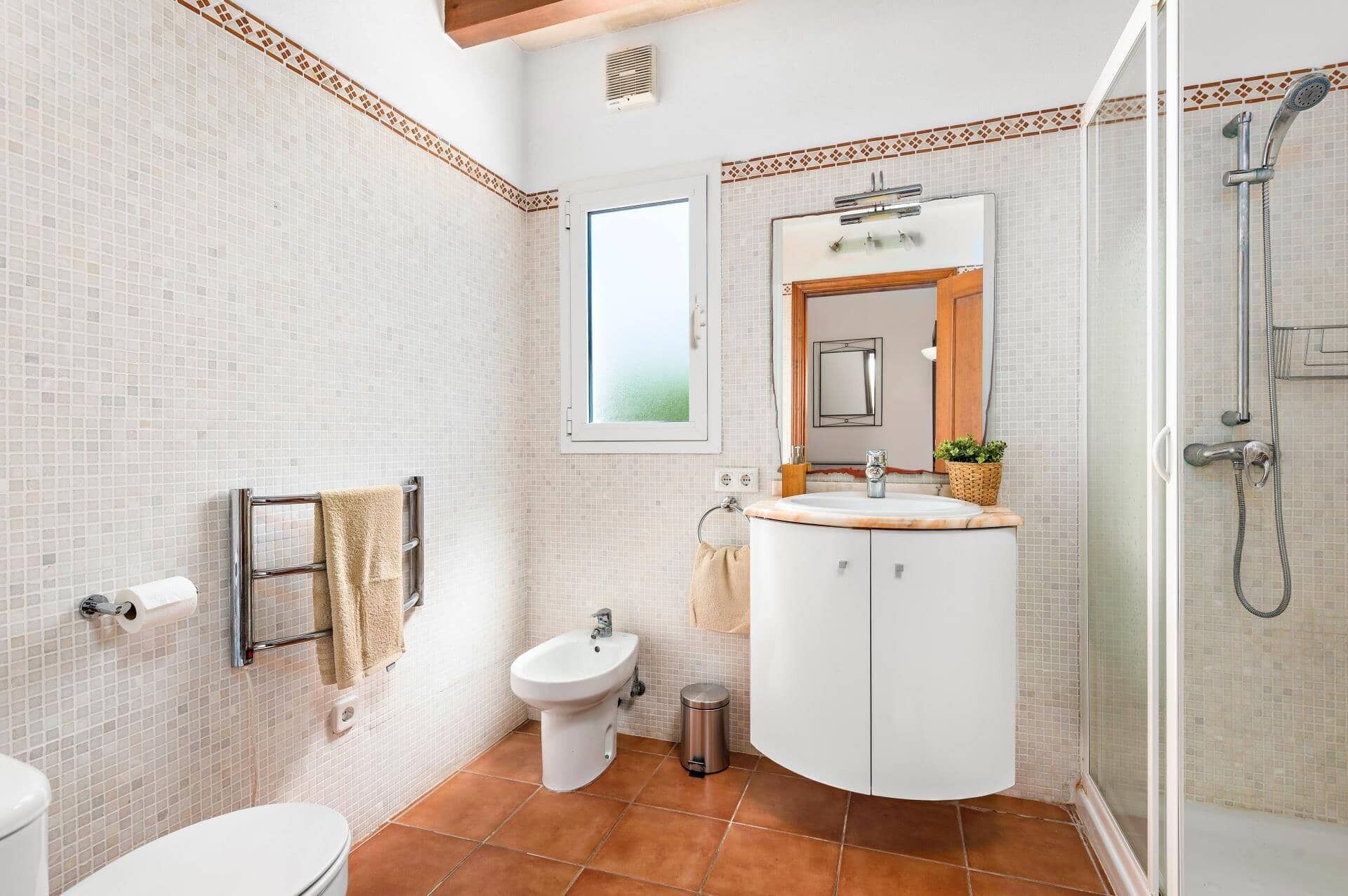 A bathroom with a toilet, bidet, sink, and shower.