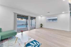 A modern living room with a green sofa, a white coffee table, and a view of a swimming pool through glass doors. - Oasis Hideaway! (Las Vegas)