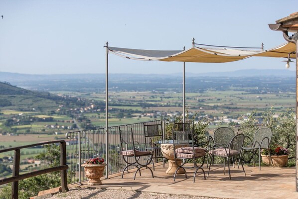 Une terrasse extérieure avec une table et des chaises, une pergola et une vue sur une vallée.