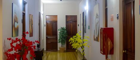 Un pasillo con piso estampado, puertas de madera y luminarias fijadas a la pared.