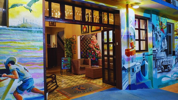 Een hotel ingang met een kerstboom, een trap en een muurschildering.