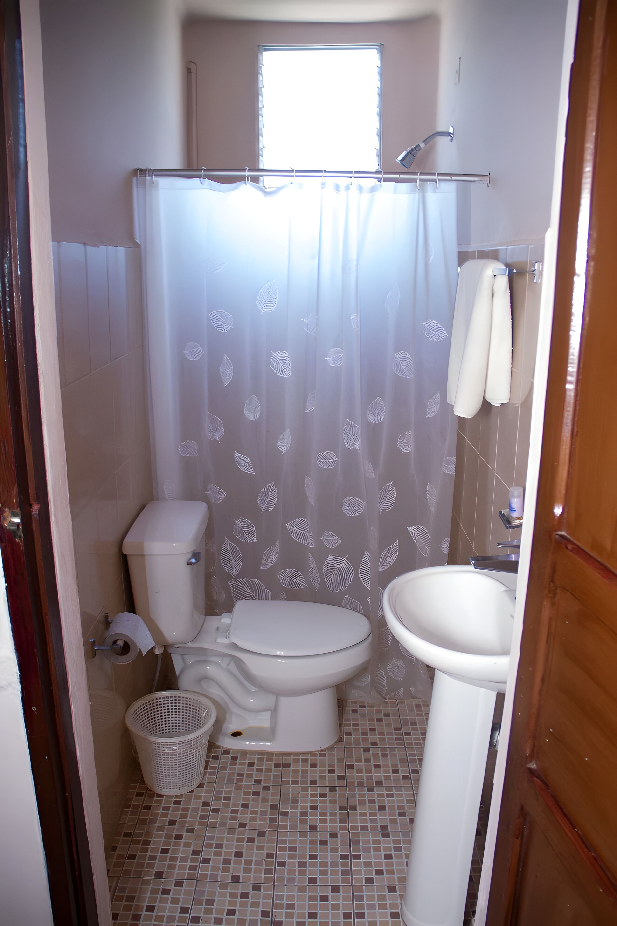 A small bathroom with a toilet, sink, and shower.