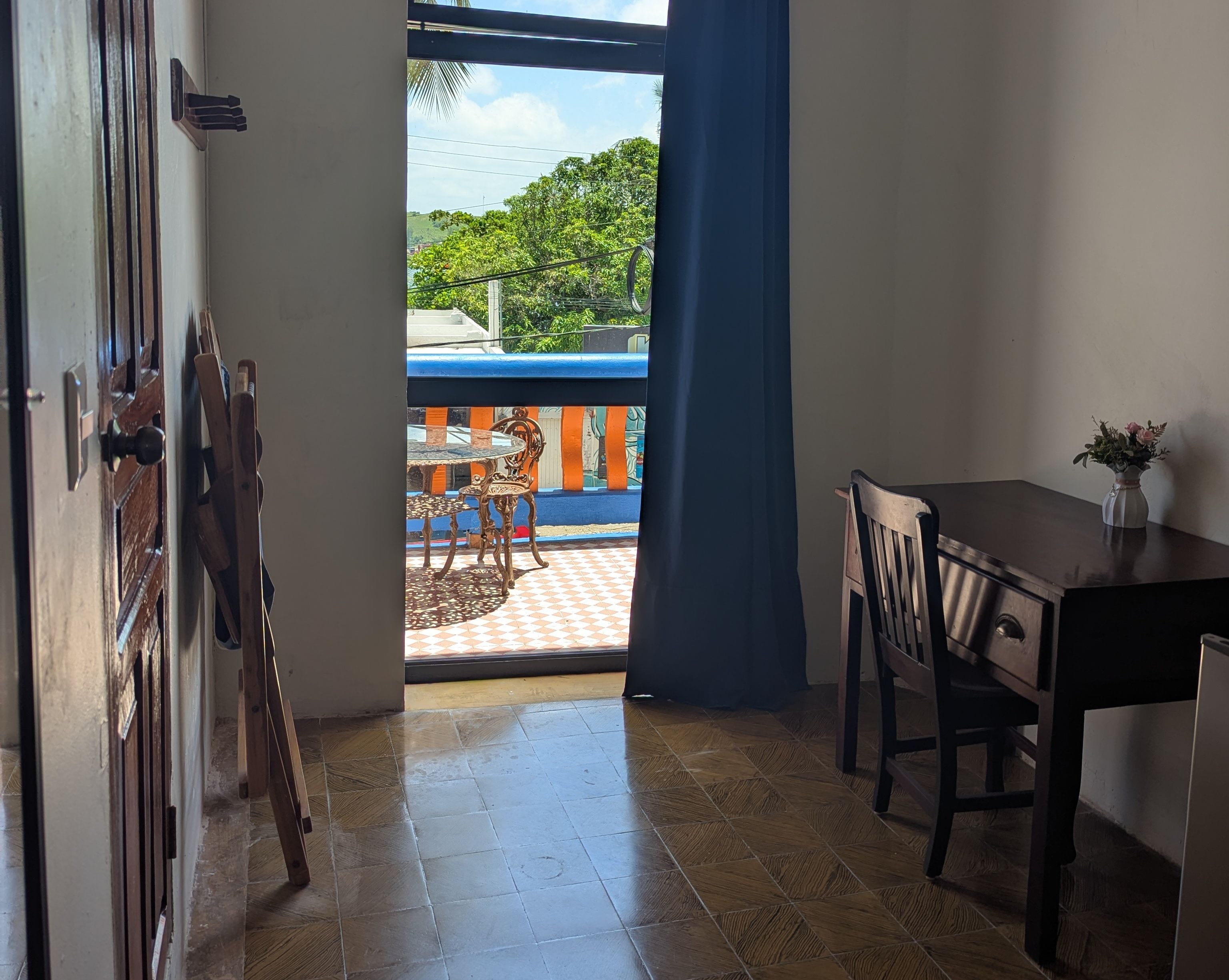 Una habitación con balcón, una mesa de comedor y sillas.