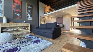 Un salon moderne avec un canapé bleu foncé, un parquet en bois et une table basse en verre.