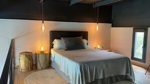 Une chambre à coucher avec un lit, des lampes de chevet, une batterie et une fenêtre.