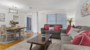 A living room with a dining table, two sofas, a coffee table, and a chandelier.