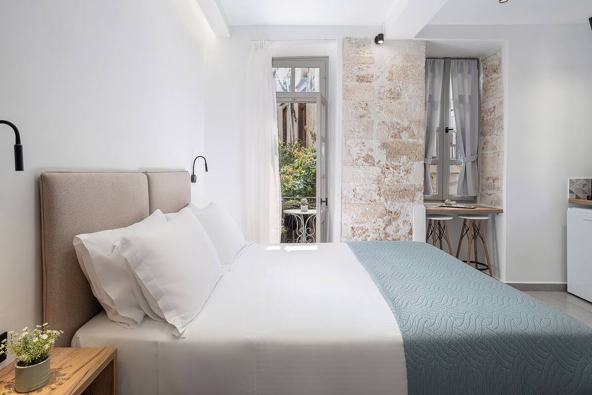Un dormitorio moderno con cama, mesita de noche y vistas a un balcón.