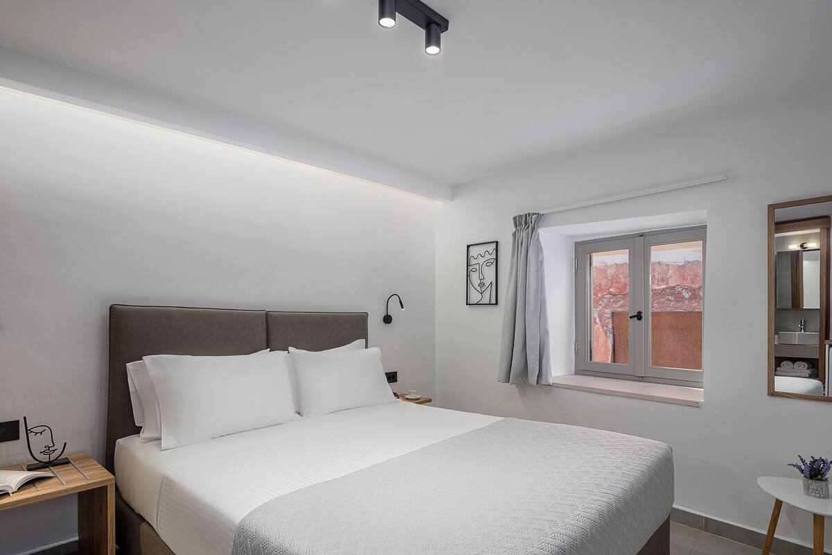 Un dormitorio moderno con una cama grande, una mesita de noche, un ventanal con vistas y una mesita auxiliar.