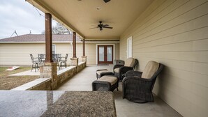 A covered patio with a ceiling fan, outdoor furniture, and a stone wall. - 3 Bedroom House w/ Outdoor Entertainment Area & Horse Accommodations (Bryan)