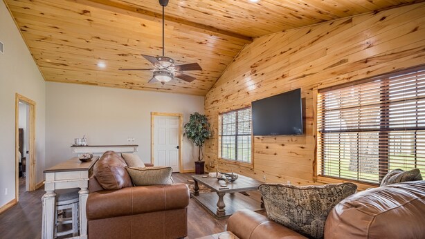 A spacious living room with a brown leather sofa, a wooden coffee table, and a ceiling fan. - 3 Bedroom House w/ Outdoor Entertainment Area & Horse Accommodations (Bryan)