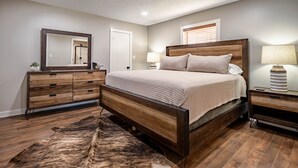 A bedroom with a wooden bed, a large mirror, a dresser, a nightstand, and a rug. - 3 Bedroom House w/ Outdoor Entertainment Area & Horse Accommodations (Bryan)