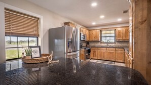 A modern kitchen with wooden cabinets, stainless steel appliances, and a granite countertop. - 3 Bedroom House w/ Outdoor Entertainment Area & Horse Accommodations (Bryan)