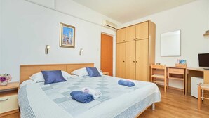 A hotel room with a bed, a desk, a chair, a wardrobe, and a TV.