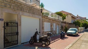 A residential street with a parked scooter, a car, and a building with a stone facade and a balcony. - 6 Double Room in Villa Kate Dadić (Dubrovnik)