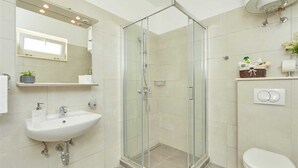 Une salle de bain moderne avec une douche à parois de verre, un lavabo blanc et des toilettes.