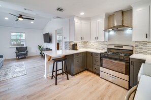 A modern kitchen with a central island, stainless steel appliances, and a dining area with a grey sofa.