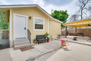 A residential house with a front porch, a door, a window, a bench, and potted plants.