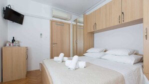 Een hotelkamer met een bed, een kledingkast en een aan de muur bevestigde televisie.