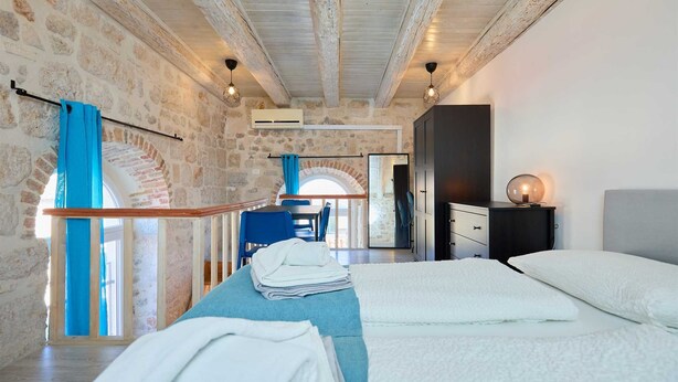 Un dormitorio con cama, escritorio y silla. Cuenta con ventana con cortinas, ventilador de techo y aire acondicionado de pared.