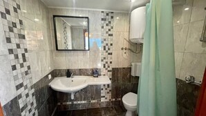 Un baño con lavamanos, inodoro y cortina de ducha.