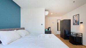 Ett modernt hotellrum med en stor säng, ett skrivbord och en stol.