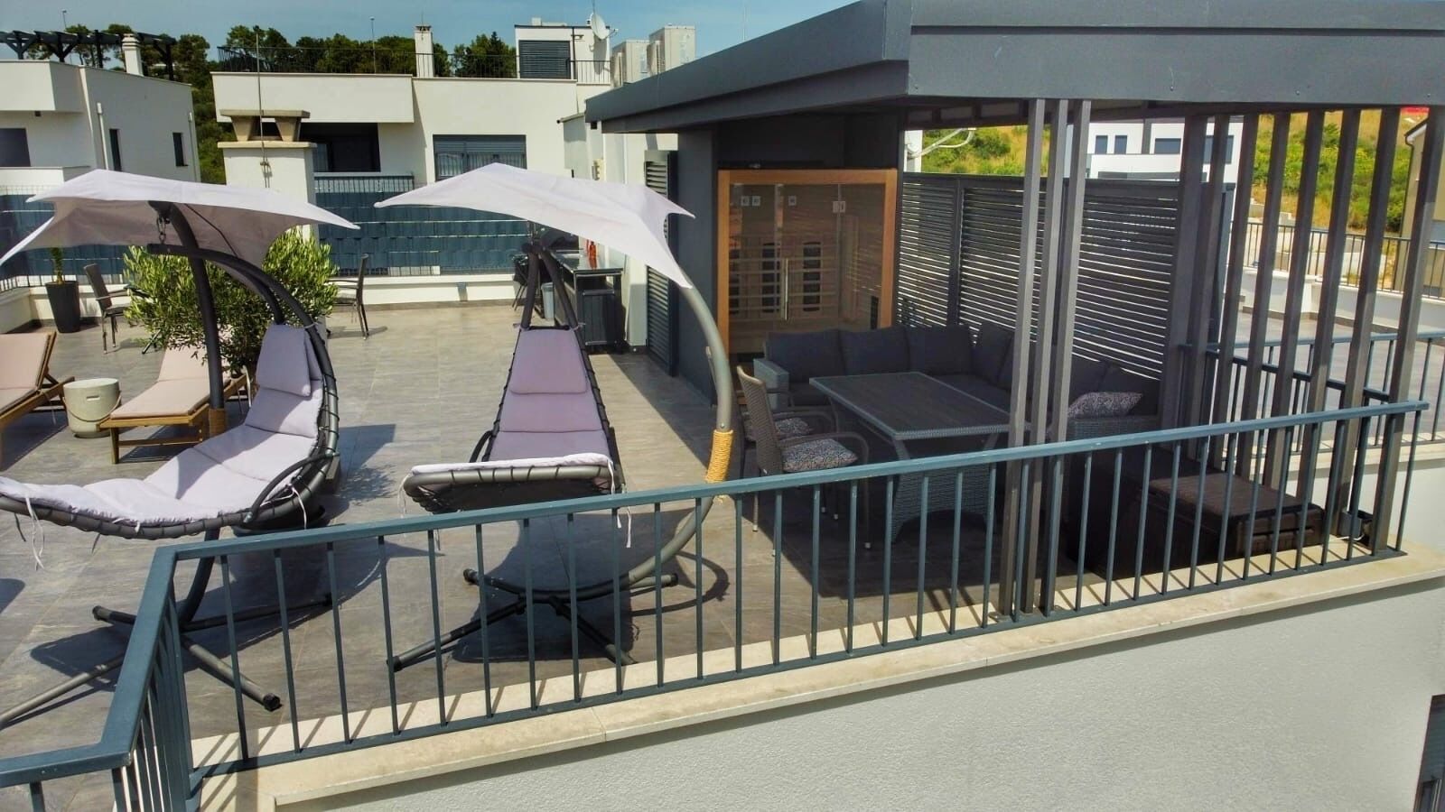 A rooftop terrace with outdoor seating, including lounge chairs and tables, and a covered area with umbrellas.