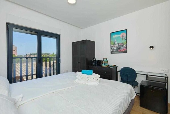 Une chambre d’hôtel équipée d’un lit, d’un bureau, d’une chaise, d’une armoire et d’un balcon avec vue.